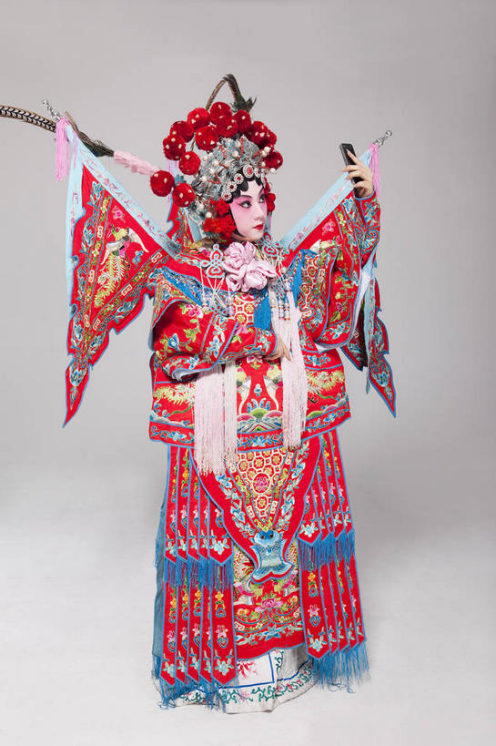 东方人,一个人,演员,站,举,打电话,竖图,室内,白天,正面,民族服装,化妆,电话,手机,亚洲,仅一个年轻女性,仅一个女性,仅一个人,表演,握,灰色背景,服装,装饰,头饰,拿,拿着,注视,黄种人,文化,通讯设备,扮演,衣服,红色,彩妆,发饰,饰品,观察,看,托,站着,握着,摄影,服饰,影棚,观看,华丽,修饰,点缀,察看,演出,衣着,穿着,关注,中国文化,摄影棚,戏剧,表演服,演出服,智能手机,京剧,配饰,戏曲,国粹,一部,皮黄,衬托,美观,雅致,雅观,衣饰,道具服,交流,年轻女性,女人,女性,亚洲人,沟通,举起,举手,举着,通话,向上举,向上伸,向上托,站立,彩图,全身,影棚拍摄,传统服装,民俗服,拍摄,京剧服饰,国剧,京戏,平剧,中国戏曲,旦角,传统文化,舞台妆,旦,刀马旦,京剧演员,武旦,角色