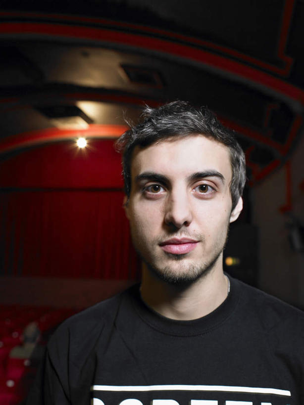 西方人,脸,头,脸颊,头发,一个人,站,笑,微笑,竖图,室内,特写,白天,正面,电影院,剧院,椅子,欧洲,欧洲人,仅一个男性,仅一个人,服装,朦胧,模糊,棕色,注视,休闲装,肩膀,仅一个年轻男性,衣服,红色,黑色,观察,看,站着,休闲,休闲服,服饰,观看,察看,关注,男人,男性,年轻男性,白种人,头部,直发,脸部,脸蛋,面部,站立,半身,彩图,剧场,戏院,影院,短发