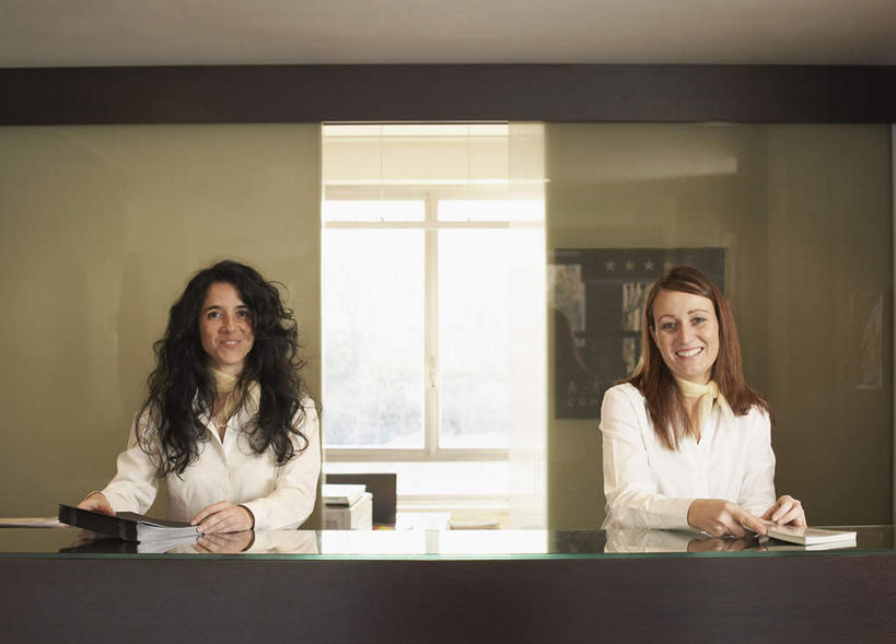 西方人,两个人,前台,服务员,宾馆,站,笑,微笑,露齿笑,横图,室内,白天,正面,工作服,制服,阅读,桌面,酒店,欧洲,欧洲人,握,墙,棕色,拿,拿着,注视,墙壁,墙面,观察,看,站着,服务台,浏览,握着,观看,察看,册子,关注,宣传,宣传册,美观,工作制服,女人,女性,中年女性,白种人,长发,卷发,直发,服务生,侍者,站立,半身,彩图,工作套服,客店,客栈,旅店,旅馆,旅舍,汽车旅馆