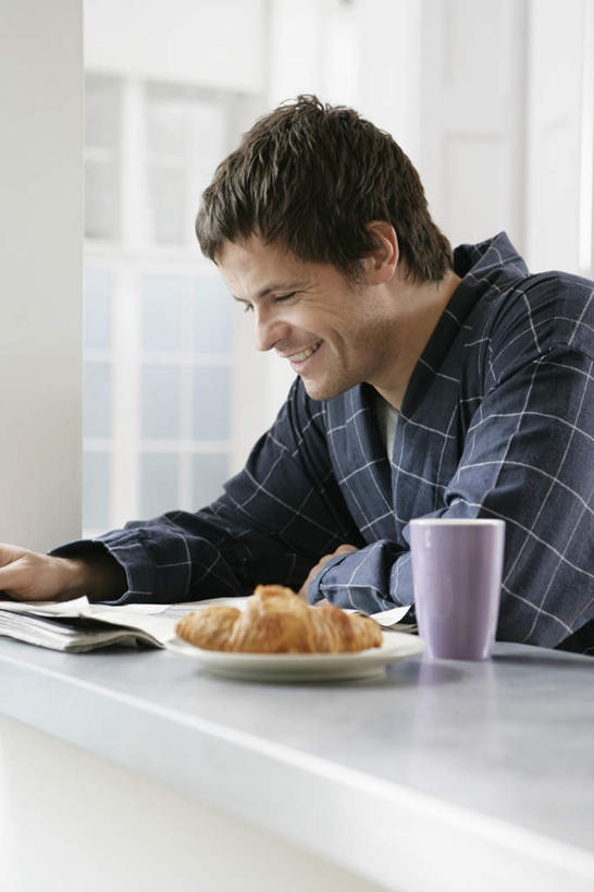 西方人,一个人,坐,笑,微笑,露齿笑,竖图,室内,白天,侧面,浴袍,阅读,餐桌,厨房,柜子,桌子,杂志,杯子,欧洲,欧洲人,仅一个男性,仅一个人,学习,注视,盒子,仅一个年轻男性,灰色,容器,水杯,橱柜,饼干,看,读书,浏览,餐台,观看,储藏,储存,关注,编制,男人,男性,年轻男性,白种人,茶杯,坐着,半身,彩图,汤帷子,浴衣,灶间,贮存