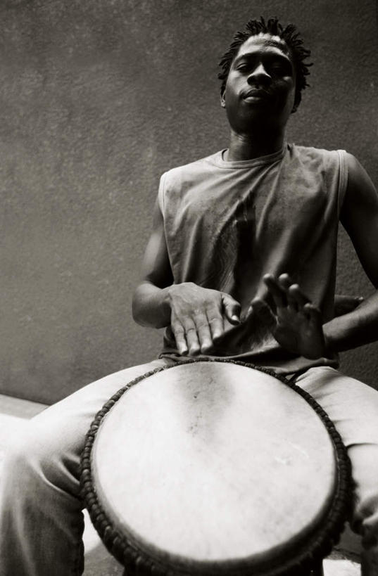 西方人,一个人,坐,竖图,室内,白天,仰视,欧洲,非洲,黑人,欧洲人,仅一个男性,仅一个人,灰色背景,服装,风俗,民俗,鼓,乐器,休闲装,仅一个年轻男性,一个,衣服,黑色,灰色,休闲,休闲服,摄影,服饰,影棚,单个,敲击,打击乐器,节奏,节拍,非洲鼓,民风,男人,男性,年轻男性,非洲人,卷发,坐着,半身,彩图,低角度拍摄,影棚拍摄,拍摄,短发