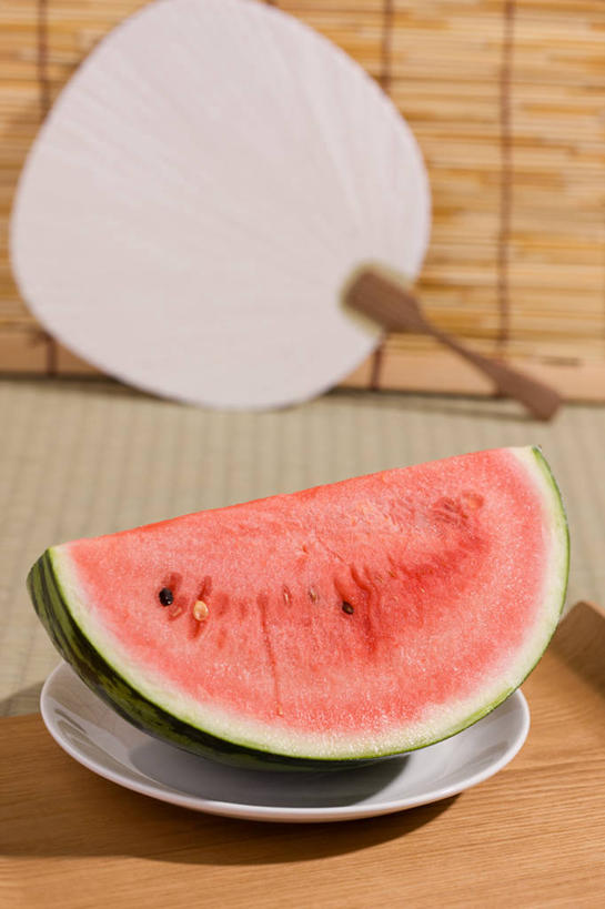 无人,竖图,室内,特写,白天,正面,西瓜,餐具,水果,阴影,新鲜,反射,碟子,盘,扇子,席子,影子,生食,食品,果实,地面,清凉,凉爽,文化,食物,一个,红色,盘子,碟,有机食品,绿色食品,单个,草席,寒瓜,彩图,和风扇,和风扇子,凉扇,传统文化