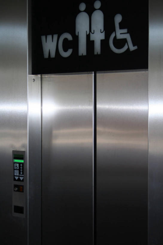 无人,三个人,病人,竖图,室内,白天,正面,卫生间,洗手间,电梯,指示牌,阴影,反射,英文,标志,工具,文字,影子,字符,字母,运输工具,标识,轮椅,复健,康复,器械,升降梯,英文字母,医疗设备,病患,医疗器械,残疾,残疾人,医疗工具,公厕,公共厕所,伤残,辅助设备,残障,弱势群体,男人,男性,年轻男性,年轻女性,女人,女性,患者,就医者,厕所,彩图,全身,升降设备,拟人