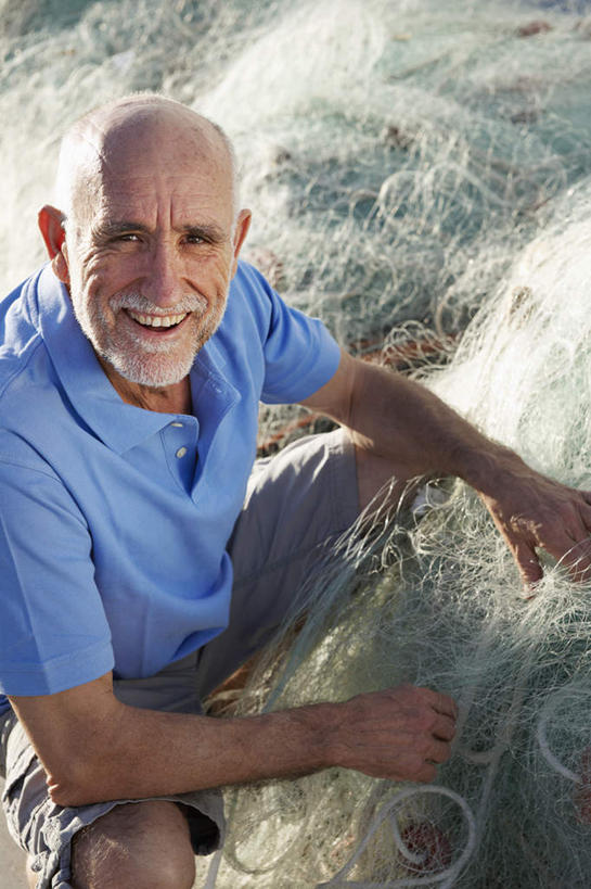 西方人,胡须,一个人,渔夫,坐,笑,微笑,露齿笑,竖图,俯视,室外,白天,T恤衫,欧洲,欧洲人,仅一个男性,仅一个人,阴影,服装,光线,影子,T恤,注视,休闲装,衣服,蓝色,阳光,观察,看,仅一个老年男性,休闲,休闲服,服饰,渔网,观看,整理,渔具,察看,关注,抓捕,捕捞,鱼网,拉网,捕捞工具,修补,老年男性,男人,男性,白种人,胡子,络腮胡,捕鱼人,打鱼人,抬头,仰头,坐着,半身,彩图,高角度拍摄