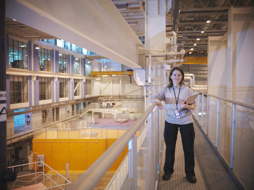 西方人,一个人,机修工,工厂,栏杆,站,笑,微笑,露齿笑,横图,室内,白天,正面,显示器,照明,欧洲,欧洲人,仅一个女性,仅一个人,阴影,服装,光线,屏幕,影子,围栏,灯光,注视,休闲装,标识,吊牌,显示屏,护栏,顶灯,灯,工人,衣服,胸牌,灯具,扶,观察,看,站着,仅一个中年女性,休闲,休闲服,服饰,观看,照亮,察看,徽章,扶着,照明设备,关注,身份,输出设备,胸章,胸卡,编号牌,雕刻牌,工号牌,胸号牌,胸徽,员工牌,女人,女性,中年女性,白种人,机械师,机修工人,站立,彩图,全身,工地,制造厂