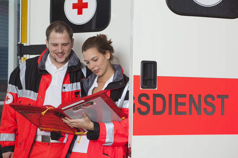 西方人,两个人,伙伴,朋友,站,笑,微笑,露齿笑,横图,室外,白天,正面,工作服,制服,友谊,合作,团队,汽车,救护车,欧洲,欧洲人,一辆,握,英文,标志,图案,文字,字符,字母,拿,拿着,注视,标识,车,红色,交通工具,观察,看,靠,靠着,站着,战略,握着,观看,英文字母,红十字,察看,急救,关注,载具,记录板,抢救,记事板,联合,合谋,工作制服,配合,协作,男人,男性,年轻男性,年轻女性,女人,女性,白种人,站立,半身,彩图,工作套服,急救员