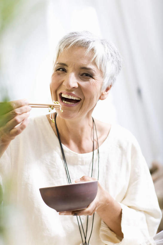 面食,面条,西方人,头发,一个人,坐,笑,吃,微笑,露齿笑,竖图,室内,白天,正面,植物,靠垫,沙发,项链,欧洲,欧洲人,仅一个女性,仅一个人,握,服装,勺子,陶瓷,面,枝条,靠枕,陶瓷制品,拿,拿着,注视,休闲装,装饰品,树,树木,树枝,衣服,白色,容器,饰品,首饰,垫子,调羹,汤匙,碗,枕头,观察,看,张嘴,仅一个中年女性,休闲,休闲服,握着,服饰,观看,储藏,察看,储存,关注,张大嘴巴,布艺沙发,虬枝,枝杈,女人,女性,中年女性,白种人,张开嘴,嚼,食,坐着,半身,彩图,贮存,短发