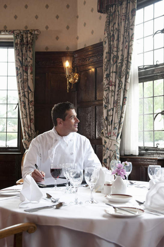 红酒,葡萄酒,西方人,一个人,厨师,宾馆,坐,笑,微笑,露齿笑,竖图,室内,白天,正面,工作服,制服,餐桌,窗户,桌子,酒店,杯子,椅子,欧洲,欧洲人,仅一个男性,仅一个人,仅一个中年男性,许多,握,写字,笔,布料,高脚杯,办公用品,红酒杯,酒类,一杯,折叠,拿,布纹,拿着,扭头,注视,水笔,玻璃窗,玻璃制品,菜单,酒,文具,桌布,饮料,排列,红色,白色,餐巾,酒杯,学习用品,台布,观察,看,转头,红葡萄酒,握着,餐台,观看,文具用品,察看,书写,葡萄酒杯,队列,关注,工作制服,保洁方巾,口布,男人,男性,中年男性,白种人,厨师长,厨子,大厨,主厨,玻璃杯,坐着,半身,彩图,工作套服,客店,客栈,旅店,旅馆,旅舍,汽车旅馆