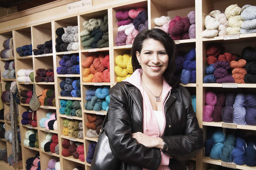 西方人,一个人,店员,商店,站,笑,微笑,露齿笑,横图,室内,白天,背景,正面,欧洲,欧洲人,仅一个人,服装,商品,挎包,休闲装,商铺,外套,顾客,货架,货物,展示架,展架,衣服,背包,手提包,毛线,站着,休闲,休闲服,皮质,成熟,美女,服饰,储物架,优雅,五颜六色,丝线,双手抱胸,皮衣,斜挎包,客户,五彩缤纷,分类,市肆,商号,年轻女性,女人,女性,白种人,商人,半身,彩图,店铺