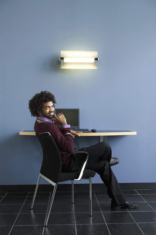 西方人,一个人,办公室,坐,笑,微笑,露齿笑,竖图,室内,白天,侧面,地板,桌子,欧洲,非洲,黑人,欧洲人,仅一个男性,仅一个人,阴影,光线,壁灯,影子,办公桌,墙,灯光,地面,靠背椅,二郎腿,注视,墙壁,灯,仅一个年轻男性,灯具,观察,看,观看,察看,双手抱头,关注,照明工具,男人,男性,年轻男性,非洲人,坐着,彩图,全身