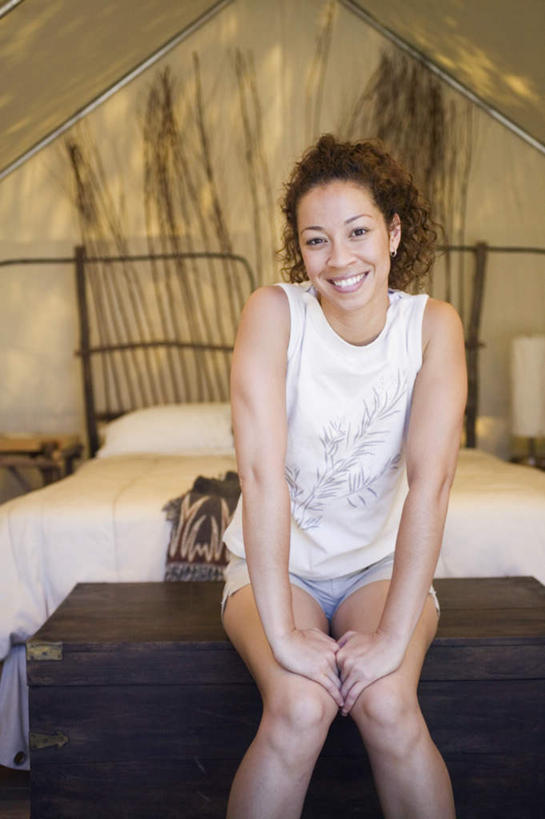 膝盖,一个人,坐,笑,微笑,露齿笑,竖图,室内,白天,正面,度假,床,非洲,双手,仅一个人,短裤,服装,木制,背心,帐篷,床单,注视,休闲装,娱乐,上衣,束发,衣服,白色,箱子,枕头,观察,看,休闲,休闲服,服饰,观看,支撑,察看,撑着,关注,年轻女性,女人,女性,非洲人,卷发,坐着,半身,彩图