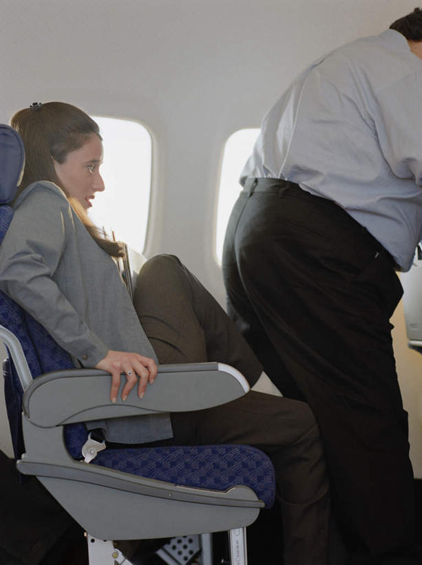 西方人,两个人,站,坐,竖图,室内,白天,侧面,飞机,欧洲,非洲,黑人,欧洲人,乘客,阴影,反射,影子,墙,交通,注视,航空,墙壁,墙面,白色,交通工具,观察,看,站着,运输,观看,察看,客机,关注,载具,男人,男性,女人,女性,中年男性,中年女性,白种人,非洲人,站立,坐着,半身,彩图