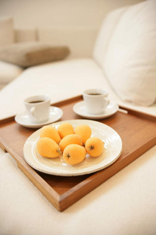 无人,客厅,竖图,俯视,室内,特写,白天,靠垫,沙发,枇杷,杯子,餐具,水果,许多,阴影,朦胧,模糊,新鲜,反射,碟子,盘,影子,陶瓷,生食,食品,果实,靠枕,陶瓷制品,很多,食物,盘子,水杯,垫子,碟,枕头,橙色,有机食品,绿色食品,起居室,布艺沙发,客堂,茶杯,芦枝,芦橘,金丸,彩图,高角度拍摄