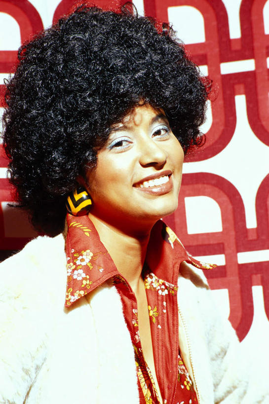 西方人,一个人,站,笑,微笑,露齿笑,竖图,室内,白天,正面,欧洲,非洲,黑人,欧洲人,仅一个年轻女性,仅一个女性,仅一个人,花纹,服装,方格,格子,图案,墙,注视,休闲装,墙壁,墙面,装饰品,衣服,红色,耳环,饰品,首饰,观察,看,站着,休闲,休闲服,摄影,服饰,影棚,观看,察看,关注,爆炸头,耳饰,年轻女性,女人,女性,非洲人,站立,半身,彩图,影棚拍摄,拍摄