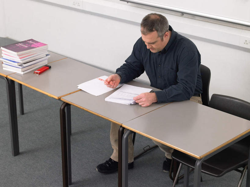 西方人,一个人,教师,坐,横图,俯视,室内,白天,桌面,桌子,椅子,欧洲,欧洲人,仅一个男性,仅一个人,仅一个中年男性,一排,握,服装,整齐,木制,笔,材料,档案,文件,纸,木椅,墙,办公用品,拿,拿着,注视,休闲装,墙壁,墙面,文具,排列,衣服,木制品,手稿,学习用品,资料,观察,看,休闲,休闲服,握着,服饰,观看,堆,文具用品,证明,察看,队列,关注,文档,男人,男性,中年男性,白种人,讲师,教授,老师,坐着,彩图,高角度拍摄,全身