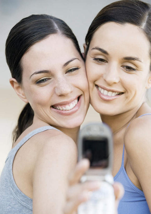 西方人,两个人,伙伴,朋友,笑,微笑,露齿笑,竖图,室内,白天,正面,友谊,电话,手机,欧洲,欧洲人,握,背心,拿,拿着,依靠,依偎,拍照,蓝色,灰色,靠,靠着,握着,自拍,友情,年轻女性,女人,女性,白种人,半身,彩图