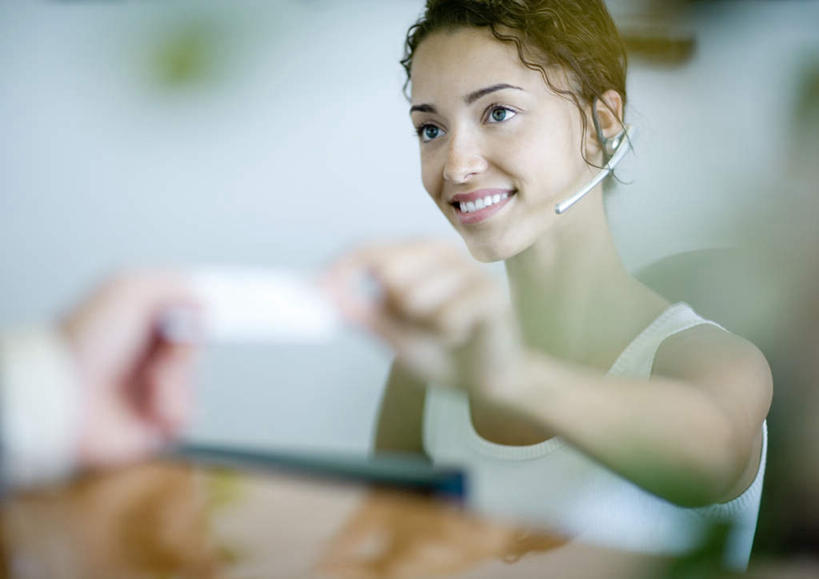 西方人,一个人,商务人士,商务女性,坐,笑,微笑,露齿笑,横图,室内,白天,正面,太阳,植物,欧洲,欧洲人,仅一个年轻女性,仅一个女性,仅一个人,递,握,阴影,套装,朦胧,模糊,传递,光线,盆栽,影子,盆景,拿,话务员,拿着,注视,绿色,阳光,自然,耳机,耳麦,话筒,柜台,看,握着,生长,成长,麦克风,关注,商务装,工薪阶层,客服人员,电话销售,年轻女性,女人,女性,白种人,白领,接线员,上班族,坐着,半身,彩图