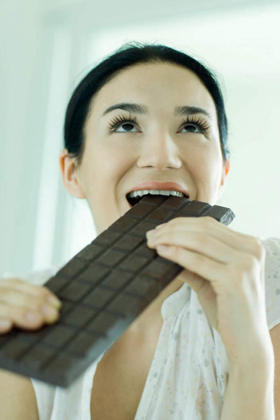 西方人,一个人,竖图,室内,白天,正面,餐桌,桌子,欧洲,欧洲人,仅一个年轻女性,仅一个女性,仅一个人,一块,握,咬,食品,糖,糖果,甜点,甜品,拿,拿着,食物,甜食,巧克力,握着,餐台,咬着,巧克力糖,年轻女性,女人,女性,白种人,半身,彩图