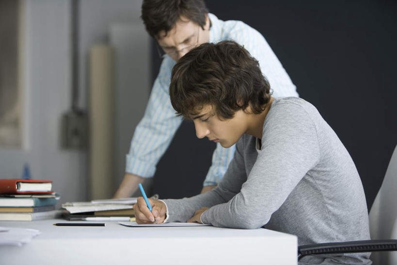 西方人,两个人,教师,站,坐,横图,室内,白天,侧面,桌子,欧洲,欧洲人,握,写,服装,笔,眼镜,注视,休闲装,书桌,衣服,课桌,观察,记录,看,站着,休闲,休闲服,握着,服饰,观看,指导,察看,关注,近视眼镜,辅导,男人,男性,年轻男性,中年男性,白种人,讲师,教授,老师,站立,坐着,半身,彩图