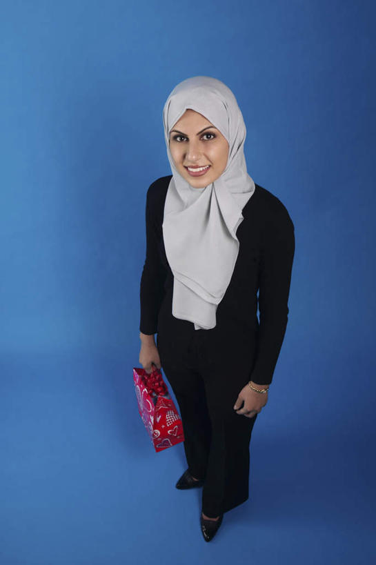 一个人,站,笑,微笑,露齿笑,竖图,俯视,室内,白天,购物,消费,袋子,亚洲,仅一个年轻女性,仅一个女性,仅一个人,握,阴影,蓝色背景,服装,反射,包装袋,手提袋,头巾,影子,购物袋,拿,拿着,注视,休闲装,衣服,观察,看,站着,休闲,休闲服,握着,金融,摄影,服饰,影棚,观看,察看,购买,关注,贸易,年轻女性,女人,女性,阿拉伯人,白种人,亚洲人,站立,彩图,高角度拍摄,全身,影棚拍摄,拍摄