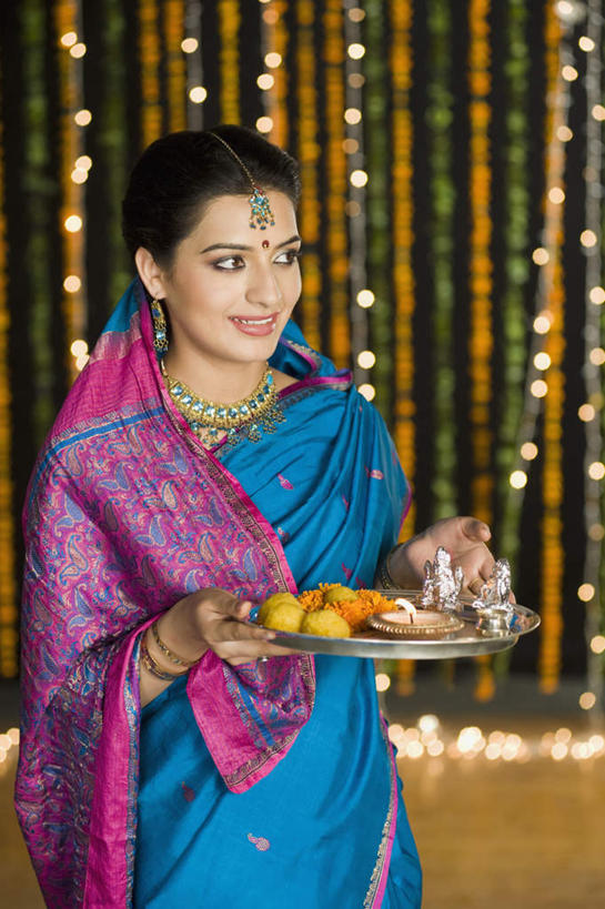 一个人,站,笑,微笑,露齿笑,竖图,室内,白天,正面,民族服装,地板,霓虹灯,餐具,水果,项链,亚洲,仅一个女性,仅一个人,一排,许多,握,节日,朦胧,模糊,庆祝,新鲜,雕像,碟子,花环,盘,神像,灯光,生食,食品,果实,地面,拿,拿着,注视,文化,木地板,灯,食物,排列,盘子,耳环,灯具,碟,观察,看,站着,仅一个中年女性,庆典,握着,有机食品,绿色食品,观看,纪念,察看,照明设备,队列,关注,印度文化,纱丽,排灯节,万灯节,女人,女性,中年女性,亚洲人,印度人,半身,彩图,传统服装,民俗服,大宝森节,屠妖节,印度灯节