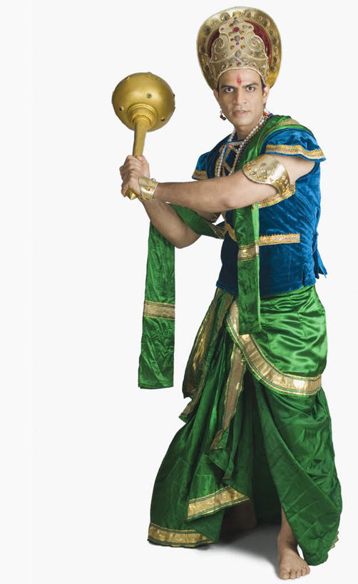 一个人,站,竖图,室内,白天,正面,民族服装,皇冠,项链,亚洲,仅一个男性,仅一个人,握,服装,注视,表演者,装饰品,仅一个年轻男性,衣服,耳环,饰品,首饰,观察,看,站着,握着,服饰,观看,权威,察看,衣着,穿着,高贵,关注,和平,印度文化,地位,权力,统治,耳饰,衣饰,符节,节钺,节杖,男人,男性,年轻男性,亚洲人,印度人,王冠,站立,彩图,全身,传统服装,民俗服