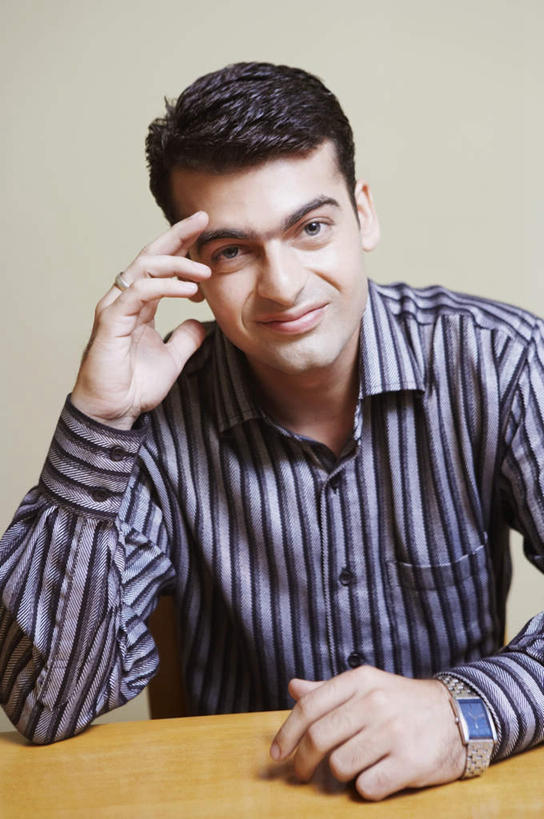 一个人,坐,笑,微笑,露齿笑,竖图,室内,白天,正面,衬衫,桌面,桌子,亚洲,仅一个男性,仅一个人,服装,木制,注视,仅一个年轻男性,衣服,木制品,观察,看,服饰,观看,察看,扶着,衣着,穿着,关注,衣饰,男人,男性,年轻男性,亚洲人,印度人,额头,坐着,半身,彩图,衬衣