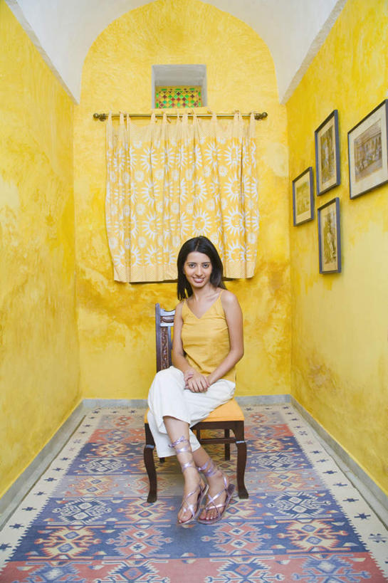 一个人,雕刻家,坐,竖图,室内,白天,正面,地毯,椅子,亚洲,仅一个年轻女性,仅一个女性,仅一个人,服装,墙,注视,休闲装,墙壁,墙面,衣服,黄色,帘子,观察,看,休闲,休闲服,服饰,观看,察看,关注,年轻女性,女人,女性,亚洲人,印度人,雕塑家,装饰画,坐着,彩图,全身