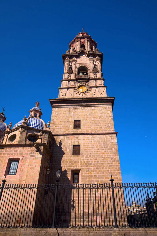 无人,教堂,栏杆,竖图,室外,白天,仰视,旅游,度假,标志建筑,城市,地标,建筑,路灯,照明,墨西哥,阴影,节日,时间,光线,时钟,影子,栅栏,墙,篱笆,围栏,钟楼,灯光,计时,文化,娱乐,建设,护栏,墙壁,墙面,灯,蓝色,蓝天,天空,阳光,钟表,天,祈祷,享受,休闲,健康,表,旅游胜地,放松,许愿,宗教,信仰,晴朗,纪念,祈求,照亮,北美,北美洲,基督教,照明设备,天主教,美洲,信念,万里无云,首府,莫雷利亚,米却肯,北亚美利加洲,亚美利加洲,塔钟,墨西哥合众国,仙人掌王国,巴亚多利德,米却肯州,莫雷利亚市,平安,钟,晴空,晴空万里,彩图,低角度拍摄,大教堂,礼拜堂