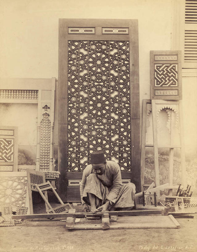 西方人,一个人,坐,竖图,室外,白天,正面,民族服装,门,帽子,雕塑,欧洲,非洲,黑人,欧洲人,仅一个男性,仅一个人,握,阴影,花纹,服装,艺术,装饰,光线,木制,雕刻,雕像,影子,拿,拿着,仅一个年轻男性,衣服,木制品,工艺品,门框,握着,服饰,纪念,华丽,修饰,美术,点缀,衣着,穿着,主题,泛黄,陈列,老照片,功能,美学,衬托,美观,雅致,雅观,衣饰,旧照,男人,男性,年轻男性,非洲人,坐着,彩图,全身,传统服装,民俗服