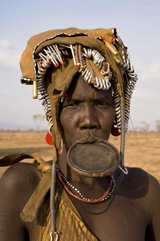 西方人,脸,头,脸颊,一个人,站,笑,微笑,露齿笑,竖图,室外,特写,白天,正面,植物,欧洲,非洲,埃塞俄比亚,黑人,欧洲人,仅一个女性,仅一个人,阴影,服装,枯萎,朦胧,模糊,装饰,光线,影子,云,云朵,枯草,云彩,注视,肩膀,草,衣服,黄色,蓝色,白云,蓝天,天空,阳光,天,观察,看,站着,服饰,仅一个老年女性,晴朗,观看,华丽,修饰,点缀,察看,平和,衣着,穿着,关注,衬托,美观,雅致,雅观,阿非利加洲,衣饰,埃塞俄比亚联邦民主共和国,和气,和善,唇盘族,摩尔西族,唇盘,老年女性,女人,女性,非洲人,头部,脸部,脸蛋,面部,晴空,站立,半身,彩图,和蔼