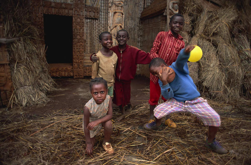 西方人,儿童,家,木屋,站,蹲,抱,笑,微笑,露齿笑,横图,室外,白天,正面,旅游,度假,游戏,纯洁,玩具,欧洲,非洲,喀麦隆,黑人,欧洲人,五个人,弯腰,握,阴影,服装,光线,影子,塑料,干草,许多人,拿,玩,拿着,注视,休闲装,娱乐,住宅,小孩,衣服,阳光,气球,塑料制品,草垛,观察,看,站着,一群人,享受,休闲,休闲服,充气玩具,橡胶,放松,可爱,童年,童趣,益智,搭,握着,服饰,抱着,观看,活动,察看,搂着,搭着,发泄,关注,消遣,智力,童真,橡胶制品,烂漫,无邪,宣泄,弯身,阿非利加洲,喀麦隆共和国,干草垛,天真,男孩,男人,男性,非洲人,蹲着,怀抱,搂,搂抱,玩耍,嬉戏,相抱,拥抱,站立,彩图,全身,茅舍,茅屋,棚屋,小木屋,小屋,男生