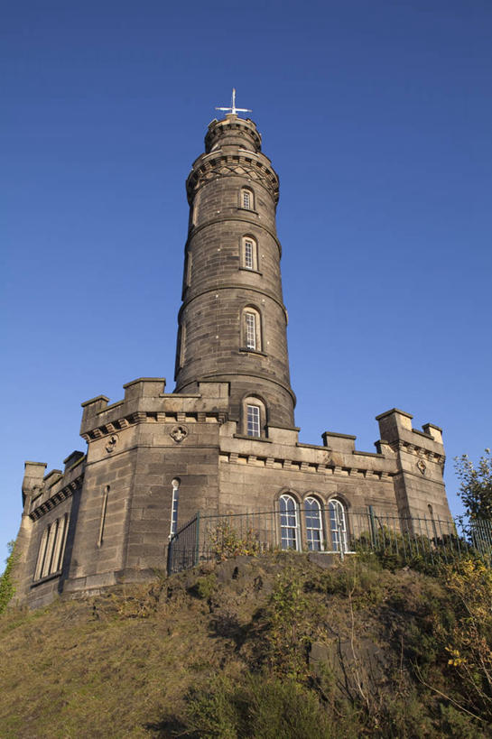 无人,栏杆,竖图,室外,白天,仰视,旅游,度假,草地,草坪,石头,山,山脉,植物,标志建筑,地标,建筑,英国,欧洲,阴影,光线,十字架,石子,影子,墙,屋顶,山峰,纪念碑,围栏,山峦,首都,顶棚,历史,娱乐,建设,护栏,苏格兰,墙壁,墙面,草,树,树木,古代,蓝色,绿色,蓝天,天空,阳光,自然,群山,天,享受,休闲,旅游胜地,放松,生长,晴朗,成长,西欧,大不列颠,大不列颠及北爱尔兰联合王国,万里无云,首府,大不列颠联合王国,日不落英帝国,古远,苏格兰王国,爱丁堡,卡尔顿山,石块,岩石,晴空,晴空万里,彩图,低角度拍摄