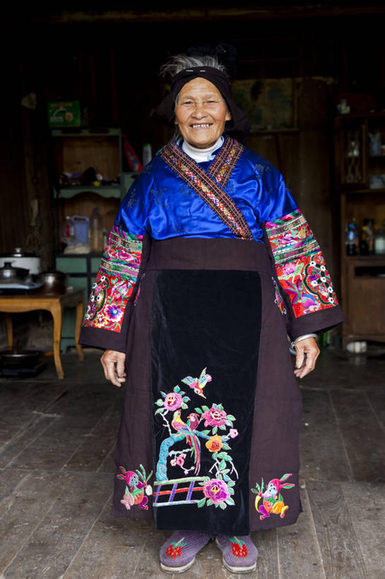 成年人,老年人,一个人,站,笑,微笑,露齿笑,竖图,室内,白天,正面,快乐,幸福,仅一个女性,仅一个人,摄影,仅一个老年女性,中国文化,肖像,贵州省,苗族,老年女性,女人,女性,中国人,彩图,传统服装