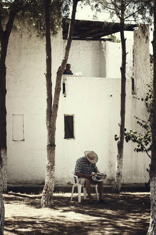 成年人,一个人,坐,竖图,室外,白天,阳台,建筑,报纸,日光,欧洲,仅一个男性,阴影,草帽,房屋,庭院,休闲装,树,放松,读书,摄影,中东,穆拉省,休闲活动,彩图,传媒