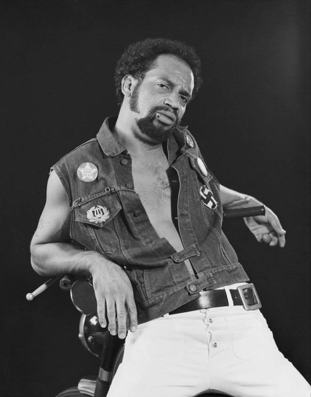 成年人,中年人,老年人,一个人,坐,竖图,黑白,室内,复古,信心,摩托车,汽车,仅一个男性,生气,标志,文字,字符,字母,陆地,牛仔裤,休闲装,标识,腰带,车,交通工具,轿车,靠,靠着,运输,摄影,生活方式,载具,肖像,叛逆,老年男性,男人,中年男性,非洲人,山羊胡,半身,党徽,纳粹万字符