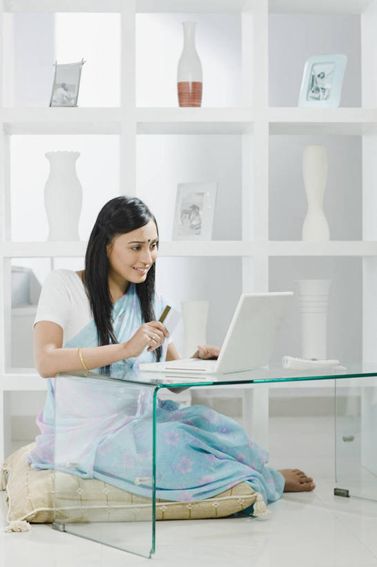 成年人,头发,一个人,家庭,坐,微笑,竖图,室内,白天,侧面,购物,通讯,信用卡,消费,笔记本电脑,技术,家具,花瓶,相框,印度,仅一个年轻女性,仅一个女性,仅一个人,敲打,首都,茶几,拿着,输入,现代,架子,黑色,打字,温暖,温馨,一家人,赤脚,零售,摄影,点击,敲击,和睦,便利,专心,起居室,付款,购买,网上银行,印度文化,纱丽,新德里,软垫,无线电技术,按键,年轻女性,女人,女性,印度人,年轻人,长发,直发,电子商务,彩图,传统服装,融洽,传统文化,美人